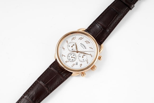 Top Hermès men's watch with white dial, brown strap, quartz movement, and leather strap, front view.