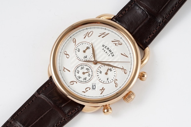 Top Hermès men's watch with white dial, brown strap, quartz movement, and leather strap, front view.