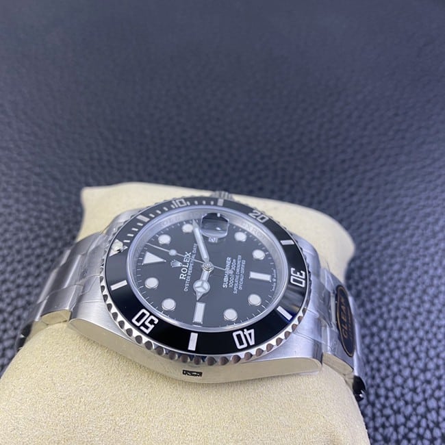 Clean factory top Rolex men's watch, black dial, steel strap, black Submariner, automatic movement, side view.